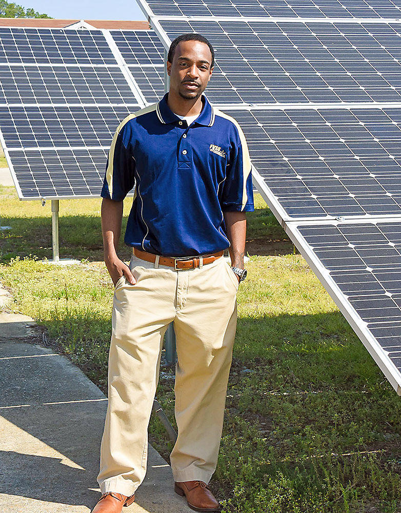 Dr. Cedric Ogden, assistant professor of engineering technology at Fort Valley State University, standing in front of solar panels installed on campus.