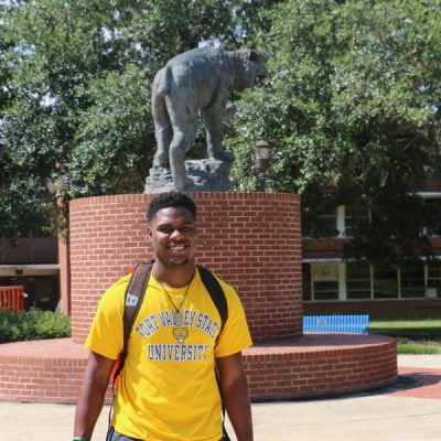 Portrait of student standing in front of statue on FVSU campus