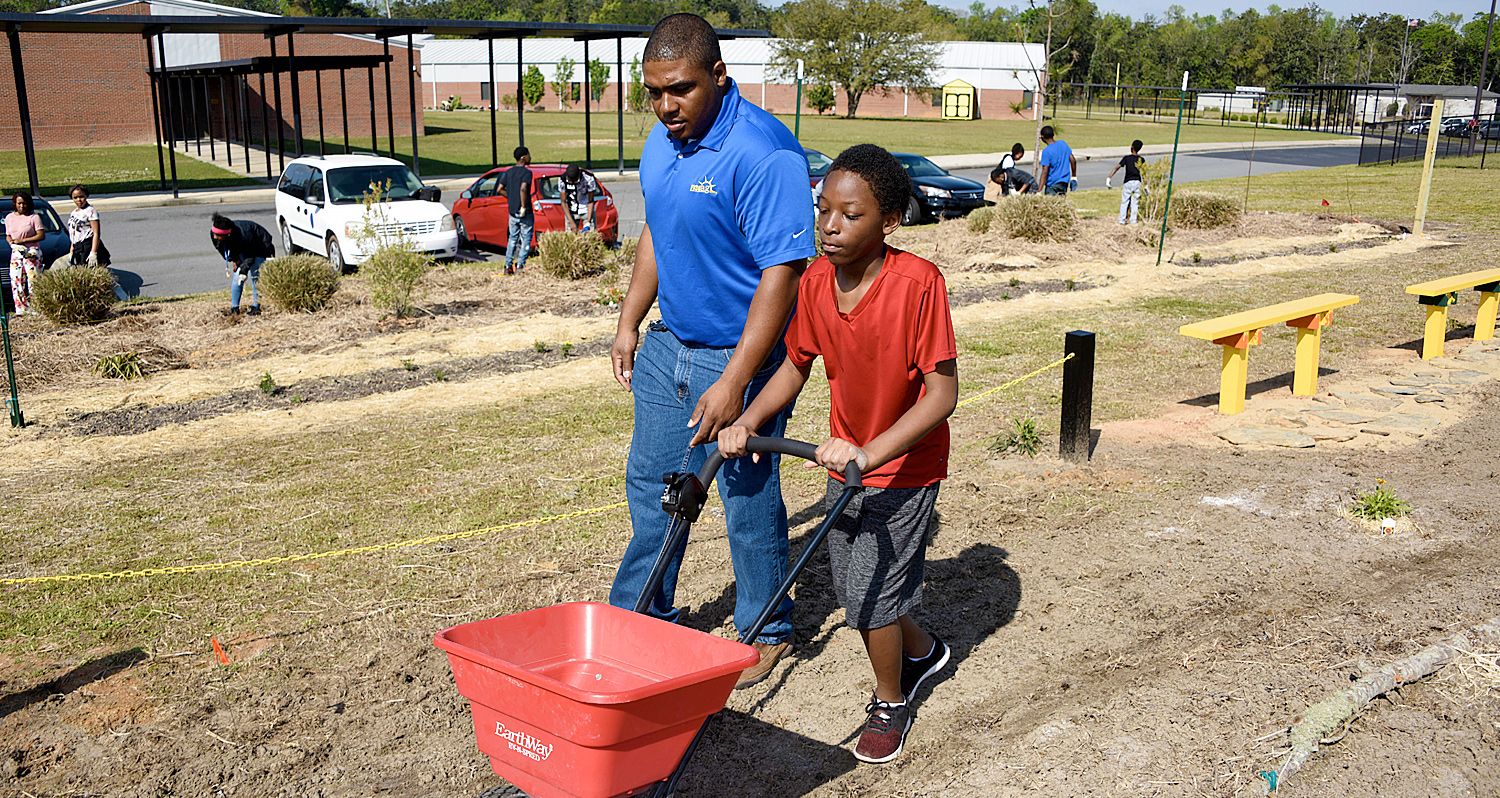 Joshua Dawson, (left) Fort Valley State University’s Lowndes County Extension agent, provides spreader instructions to Anthony Aikens, a student attending J.L. Newbern Middle School in Valdosta.