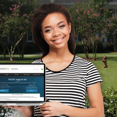 Young woman holding laptop and smiling at camera