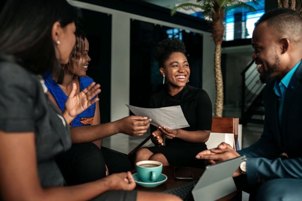 Candid happy moment between four work colleagues seated together in atrium