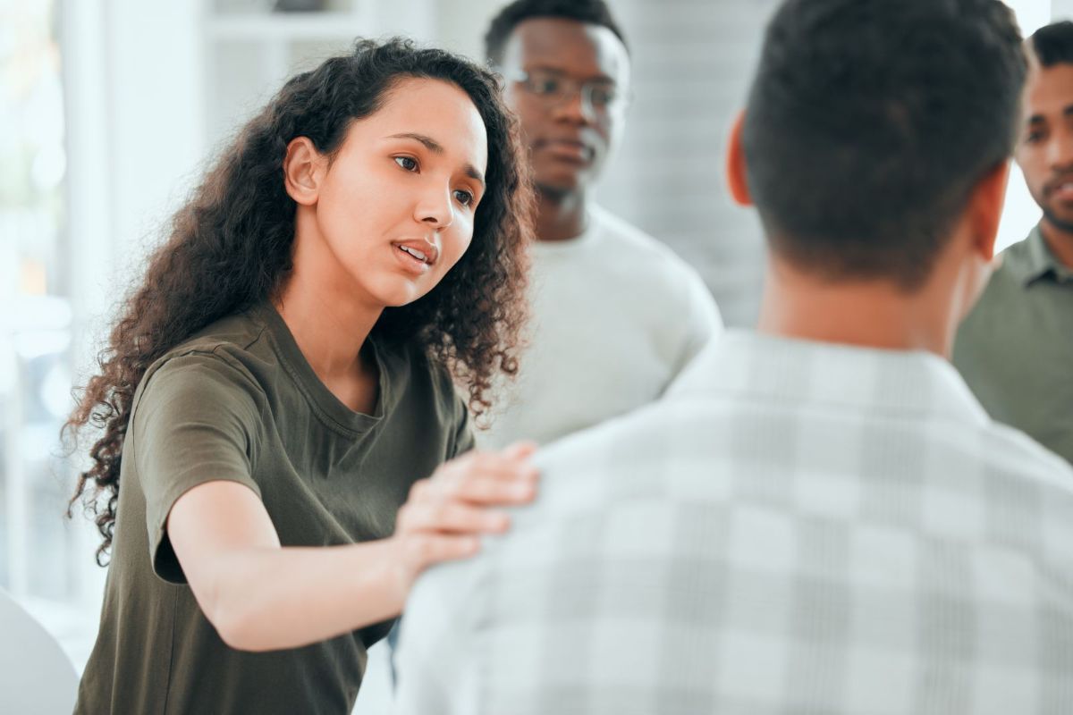 young woman sitting and comforting a member of her support group