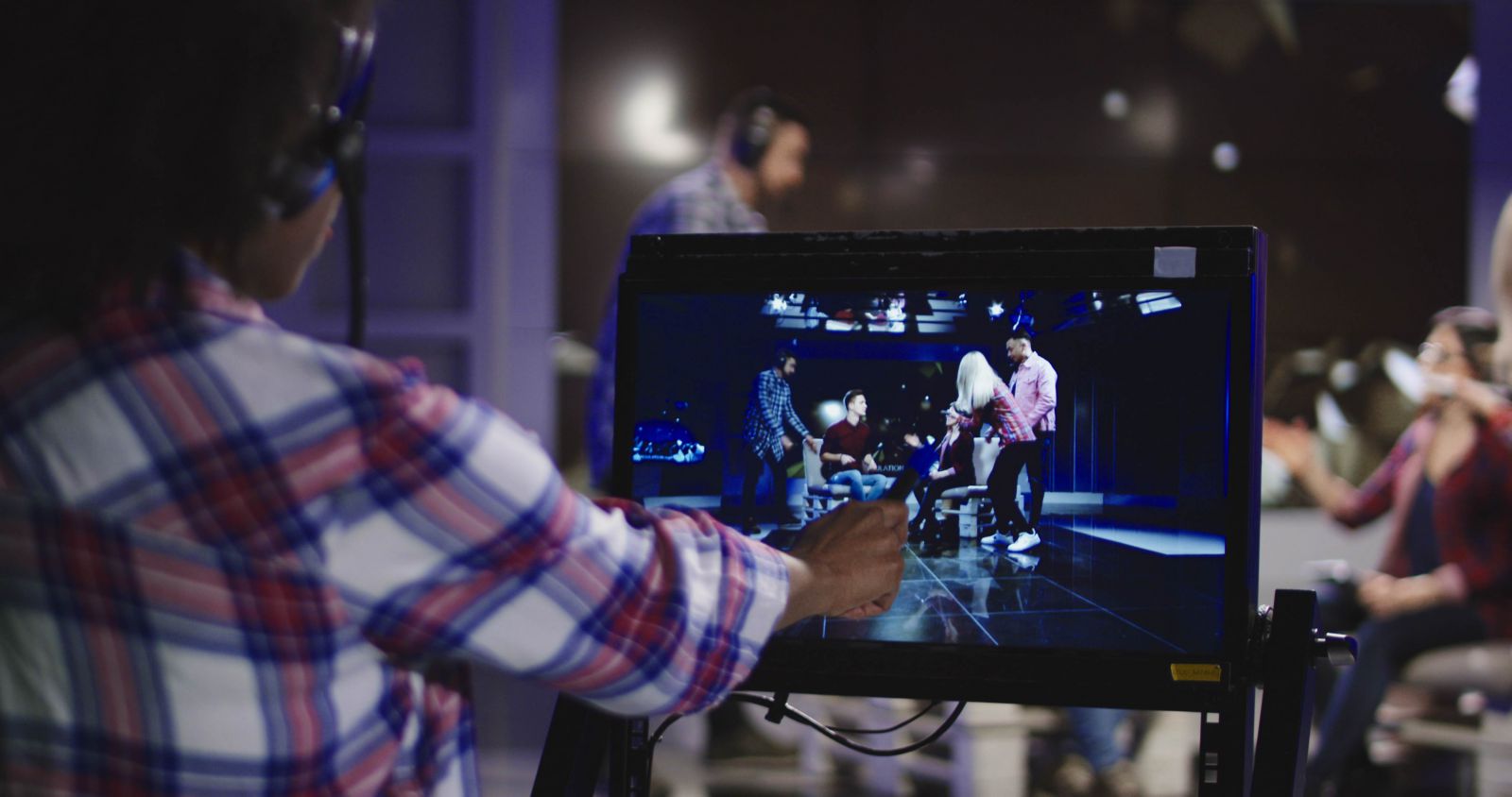 Student pointing to a production monitor recording three actors