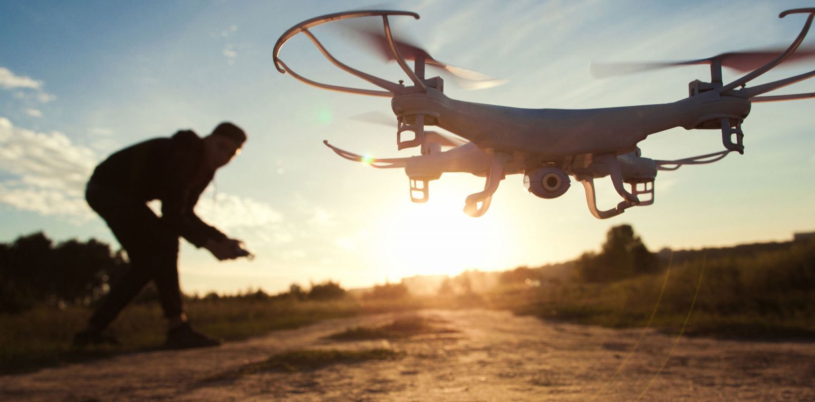 Young man flying a drone at sunrise