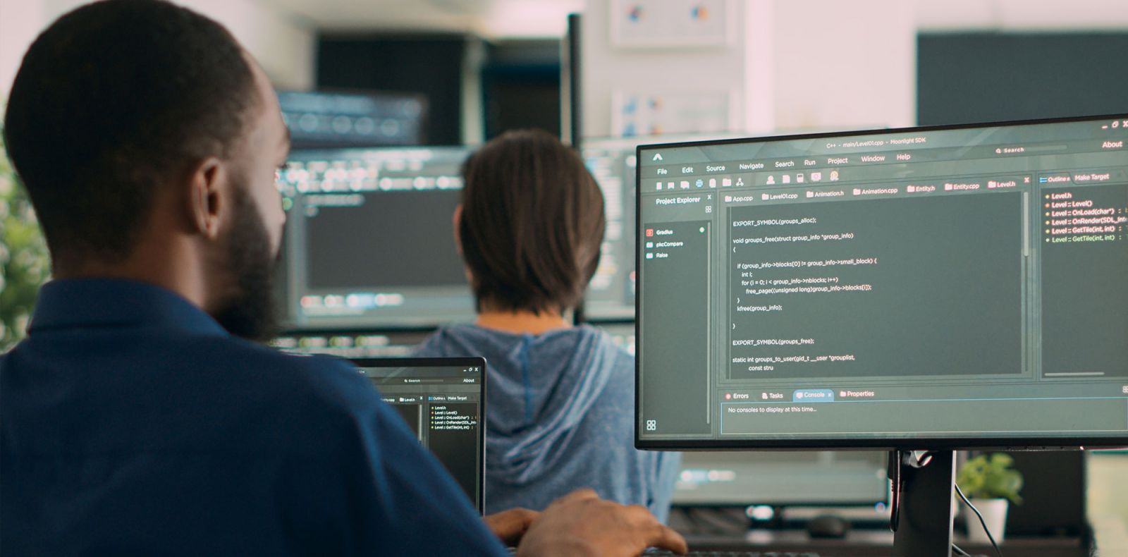 Student writing computer code infront of large monitor