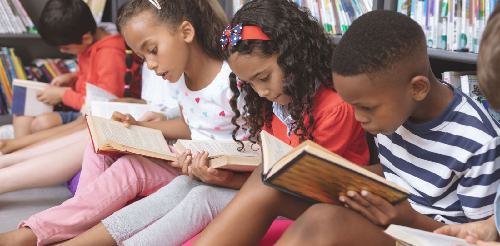 Young children seated on floor reading books