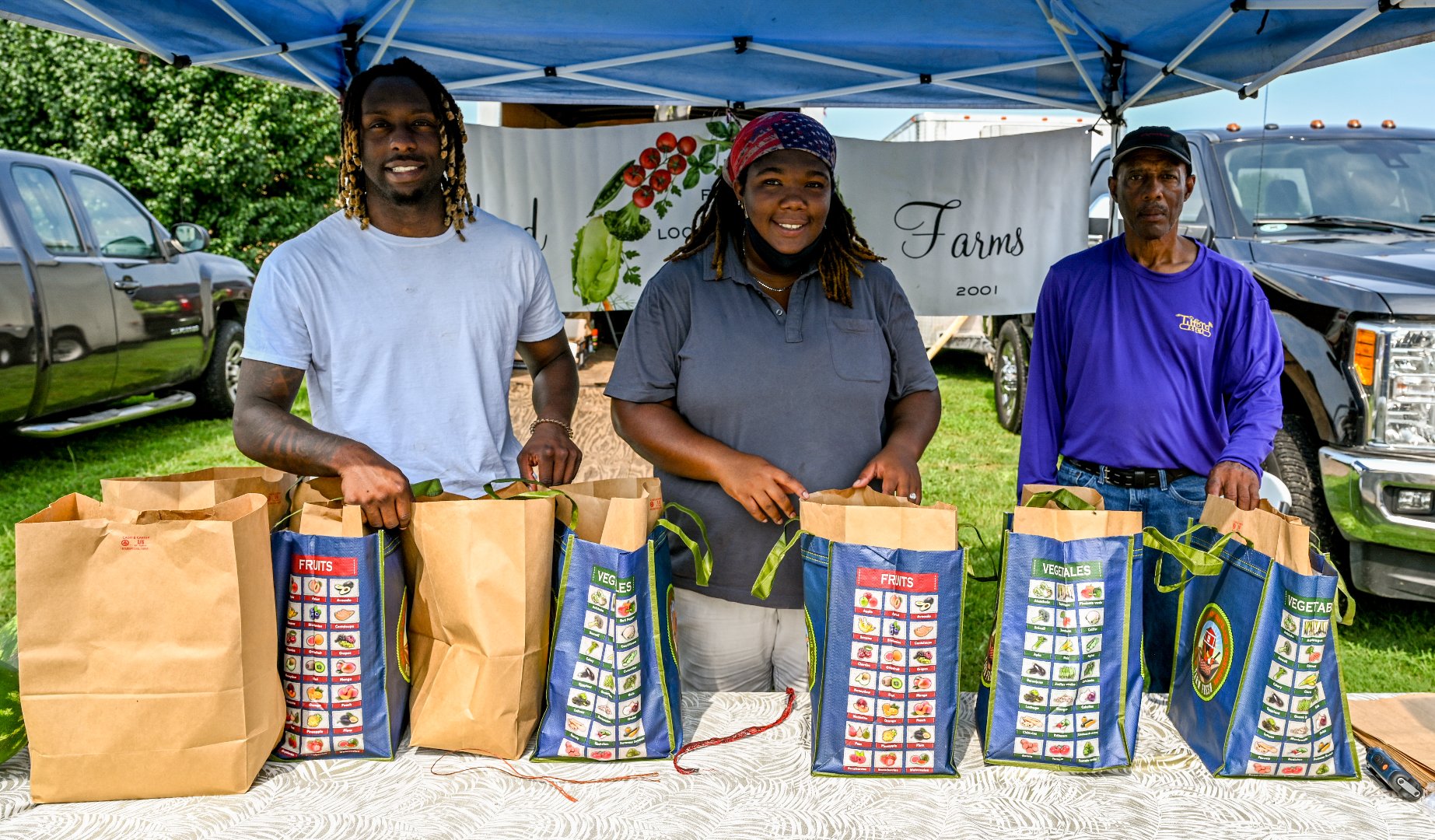 Farmer Robert Taylor, right, and FVSU students Columbus Alderman and Shaneil Allen prepare produce to distribute to customers at the farmers market in Houston County.