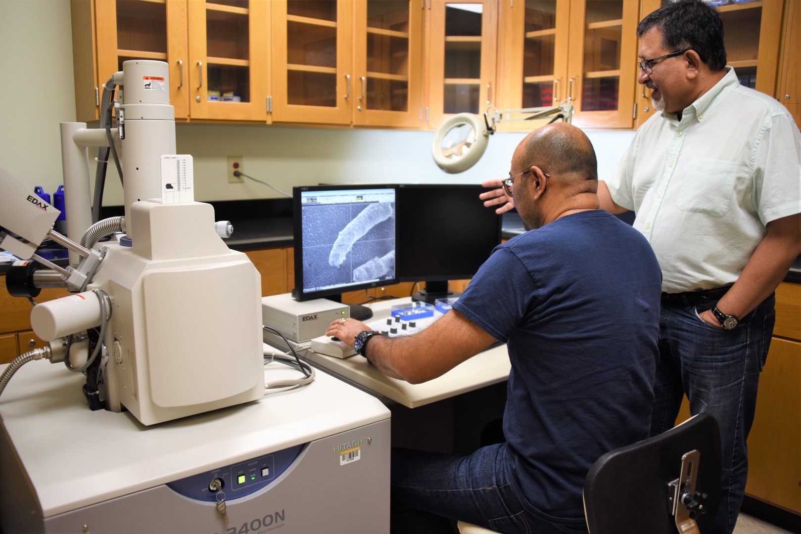Dr. Nirmal Joshee (standing), a Fort Valley State University plant science professor, and Brajesh Vaidya (sitting), a FVSU research assistant, examine an Aronia leaf using a Hitachi scanning electron microscope.