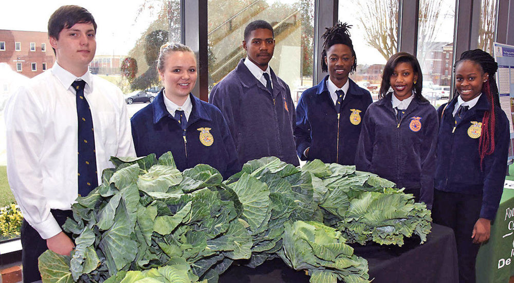 Members of the Twiggs County Future Farmers of America (FFA) chapter, show home-grown bunches of collard greens and cabbage given away as door prizes at the Farm, Home and Ministers Conference Feb. 21.