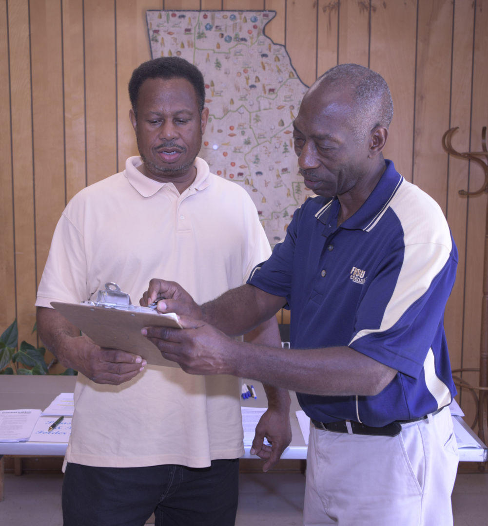 Ricky Waters, Fort Valley State University’s Macon County program assistant, (right) reviews U.S. Department of Agriculture (USDA) information with Macon County farmer Kyle Jones (left) during the Beginning Farmers Workshop in Oglethorpe on June 29.
