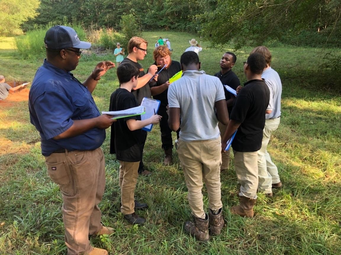 FVSU alum Joseph Nesbit (left) outdoors working with a group of students.