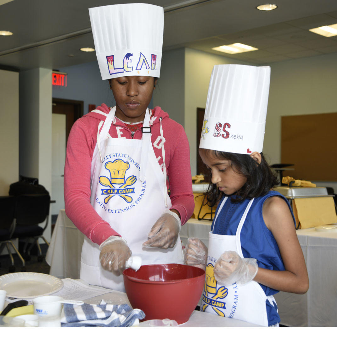 Leah Howard (left) and Sneha Singh (right) mix batter to make blueberry pancakes during the CHEF Camp at Fort Valley State University’s Family Development Center on July 18.