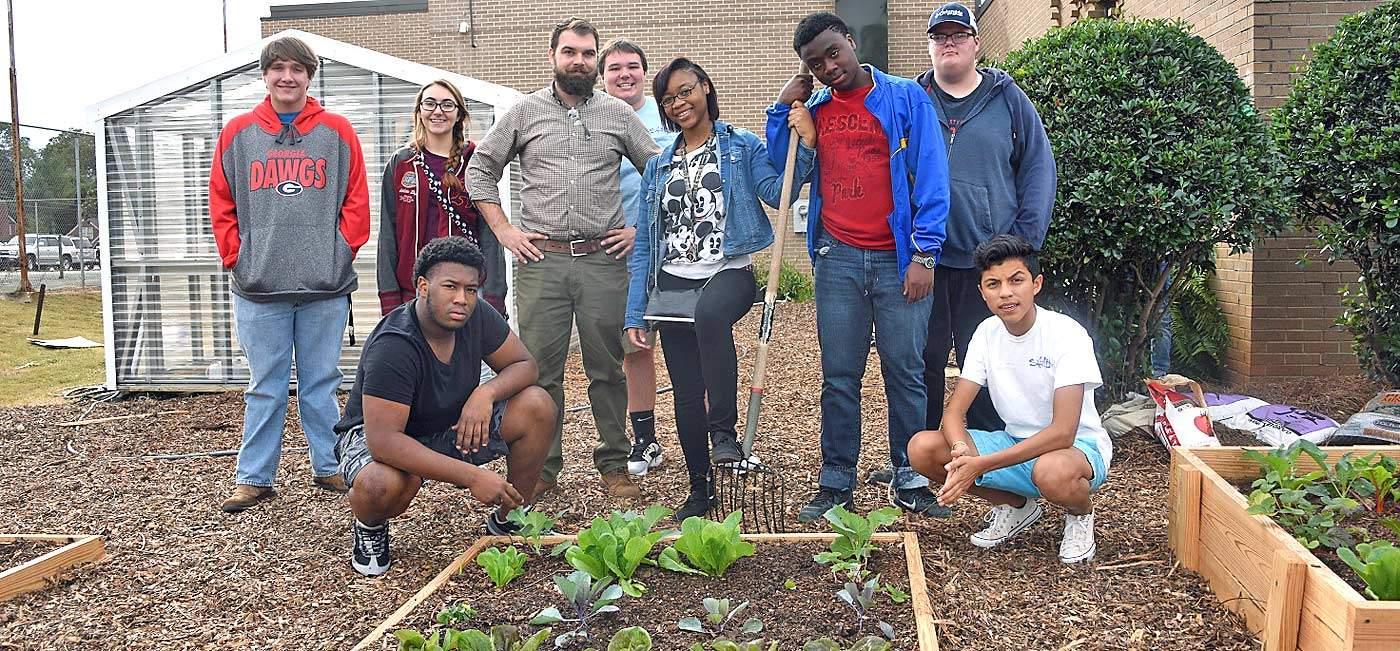 Fort Valley State University alumnus, Brandon Gross, stands with students overlooking their raised bed garden.