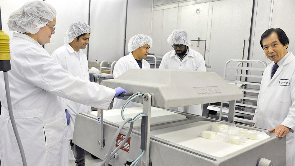 Dr. Young Park, coordinator and professor of Fort Valley State University’s Food Science Program, (far right) assists students packaging goat cheese, using a double chamber vacuum packaging machine in the Georgia Small Ruminant Research and Extension Center on campus.