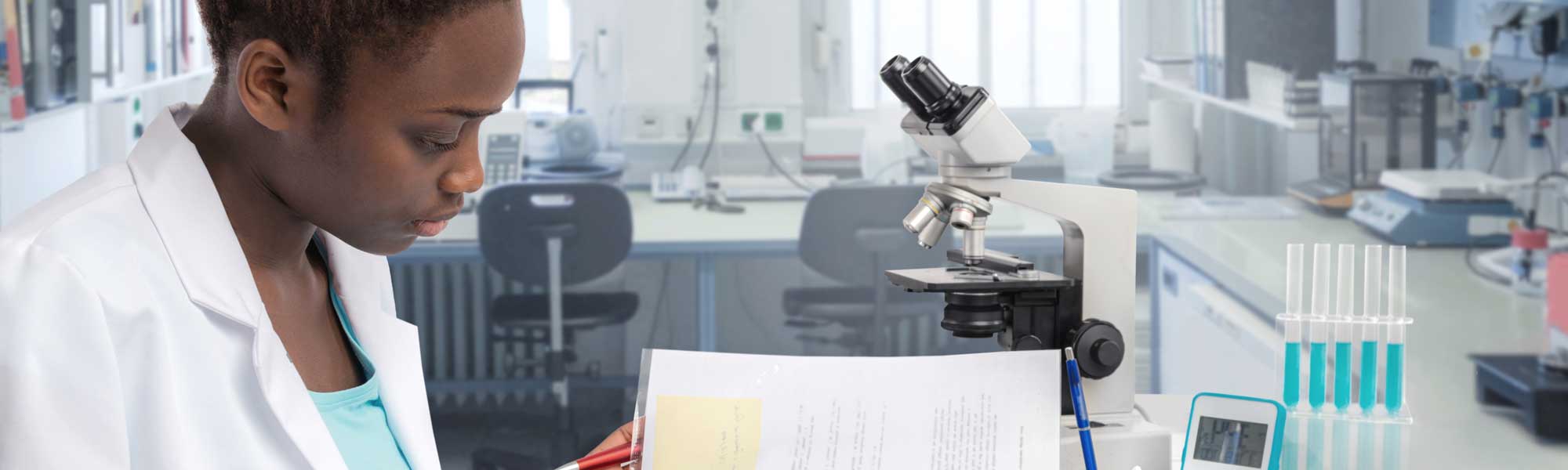 Young woman seated at lab table with microscope