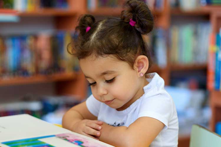 Young girl reading book in classroom