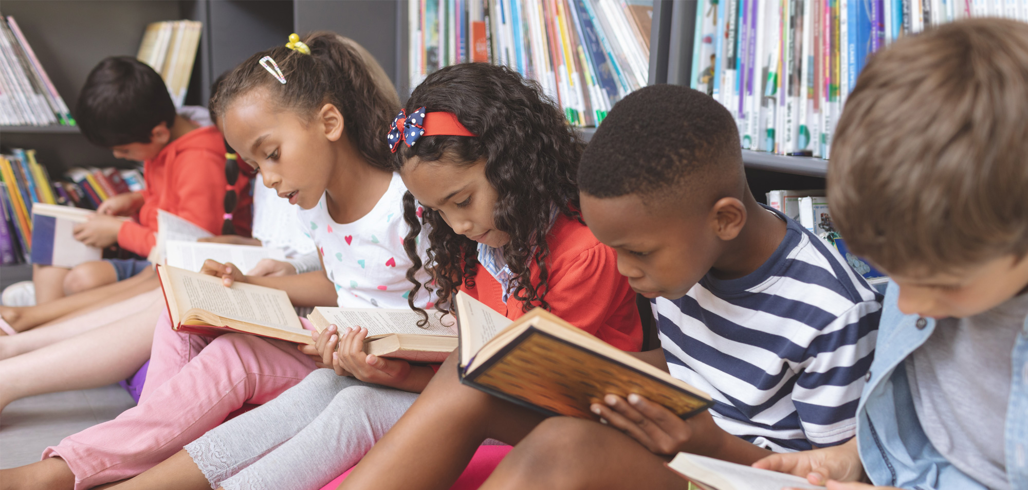 Children seated on the floor reading books