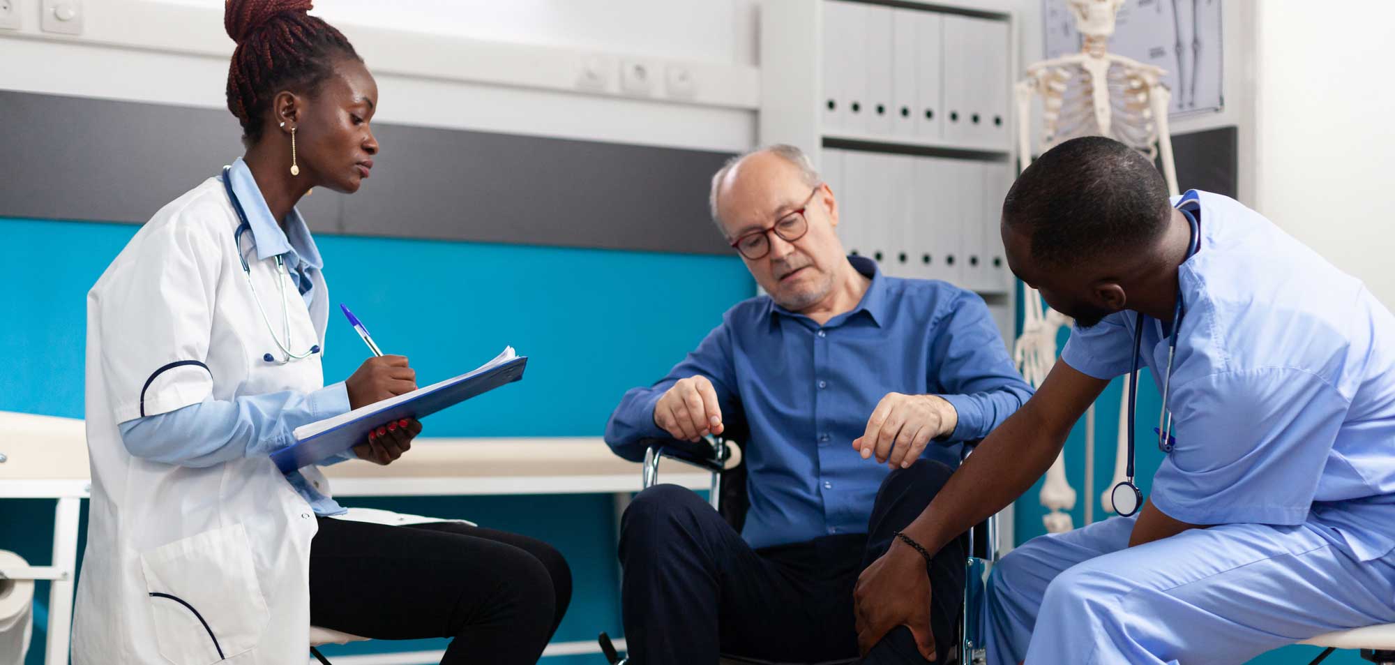 Two nurses giving exam to man in wheelchair