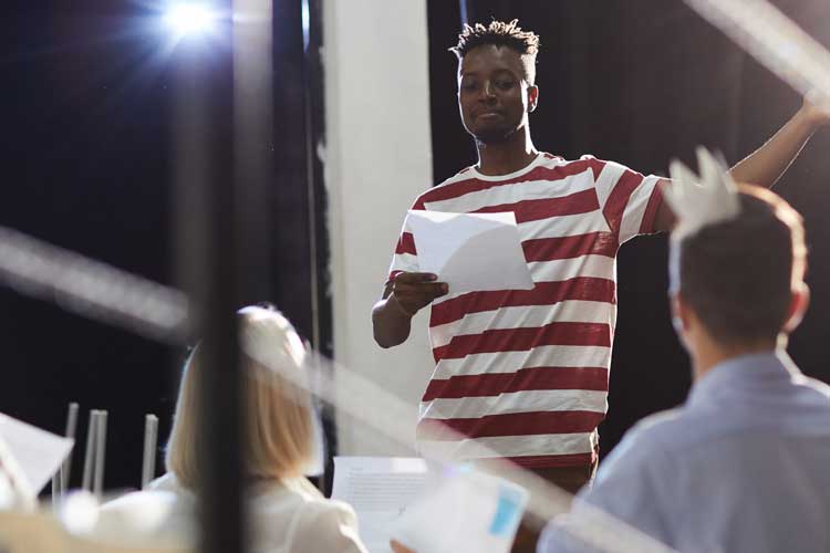 young man in spotlight auditioning for two other people